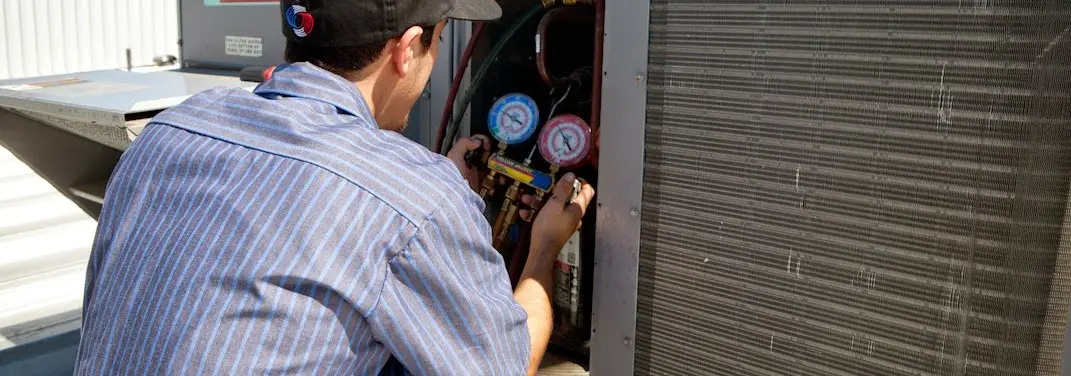 HVAC technician servicing a condenser unit in Palmer