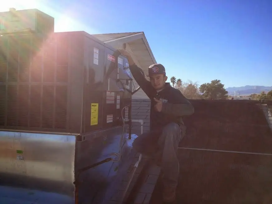 HVAC technician performing Air Duct Cleaning on a rooftop unit in Palmer